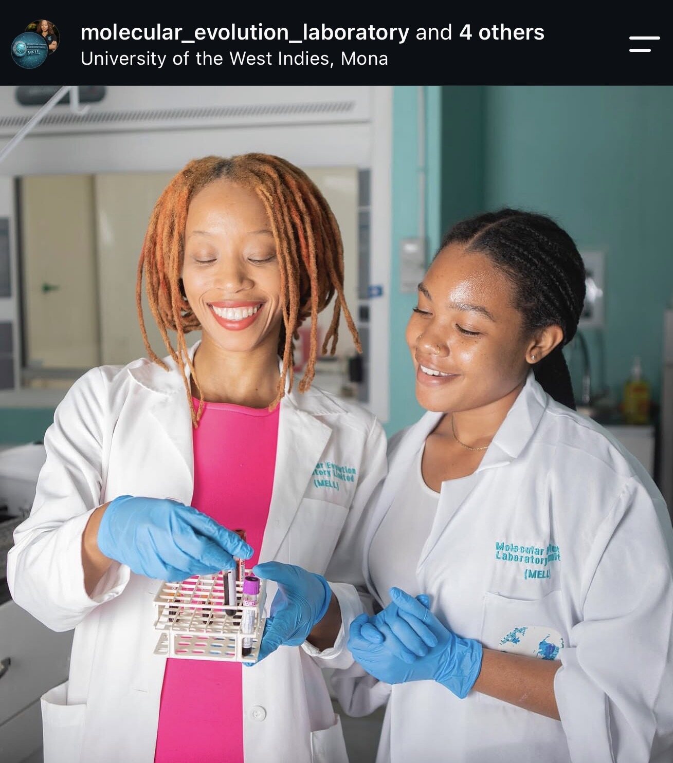 Two MELL laboratory professionals holding a rack of specimen tubes